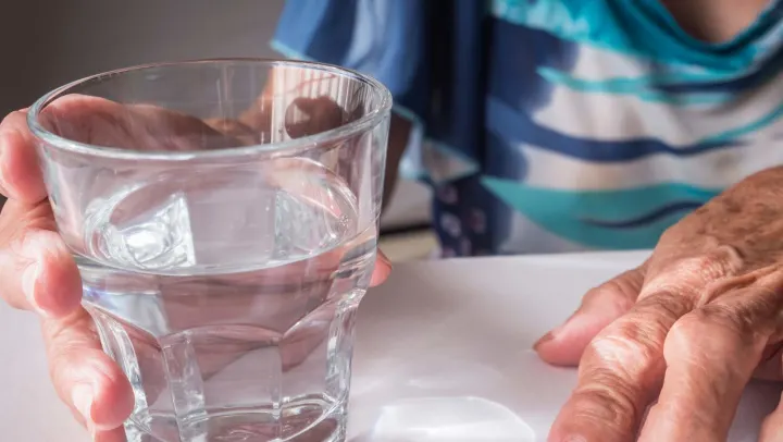 elderly man holding cup of water